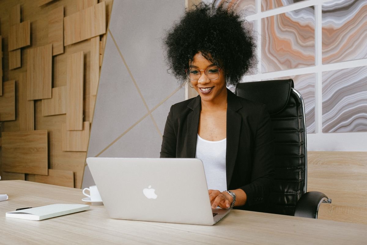 Une professionnelle souriante prépare son parcours sur son ordinateur portable
